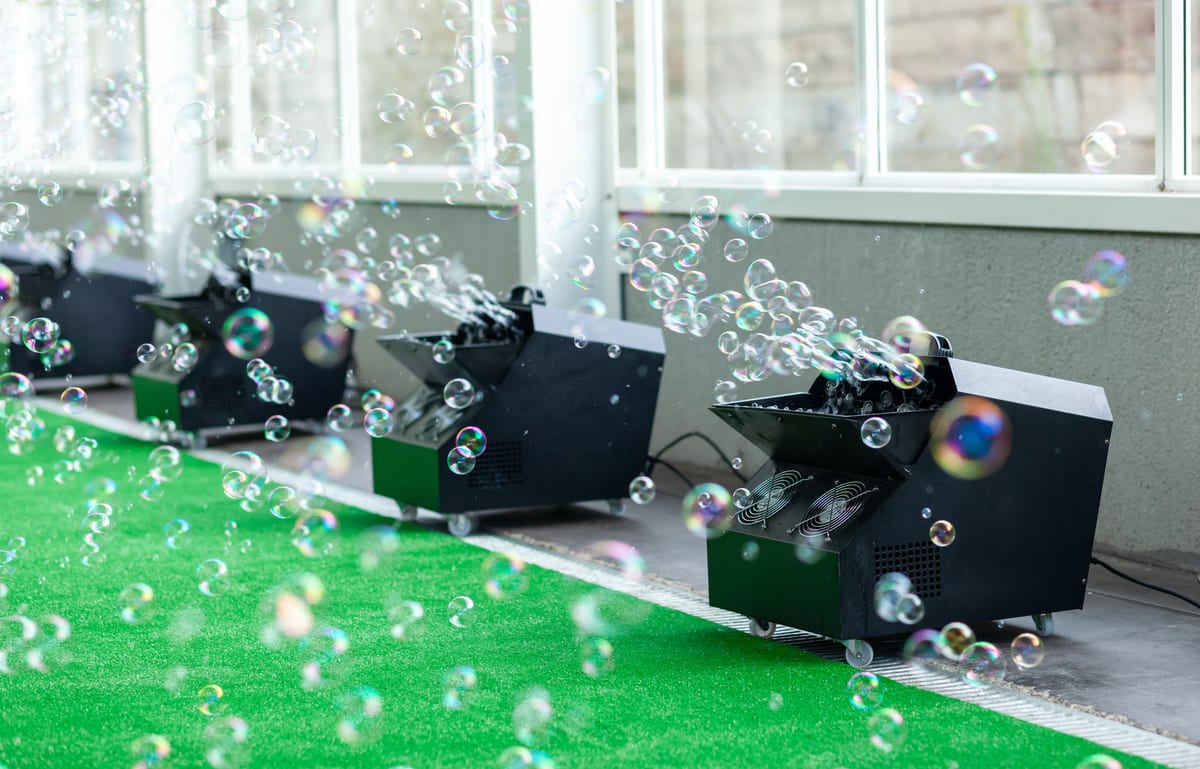 Hire bubble machine — bubbles float from machines on green surface for parties and events in Johannesburg, Sandton and Randburg